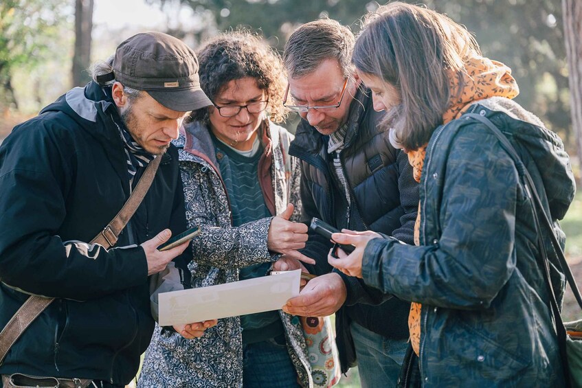 A group of people outdoors, some holding a map or paper, possibly discussing a route or location. 4