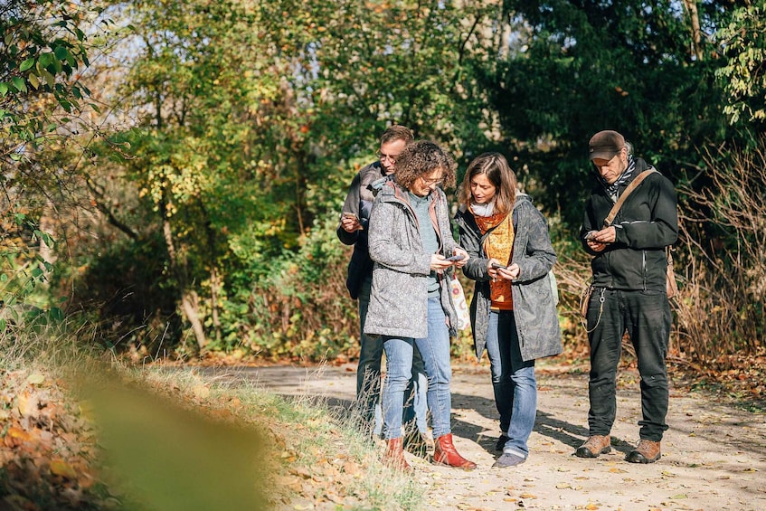 A group of people standing on a dirt path surrounded by trees and foliage. 2