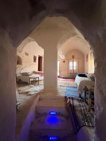 An arched passageway leading to a bedroom with a bed, a chair, and a rug. 2