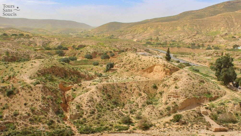 A rugged landscape with rolling hills, sparse vegetation, and a winding road. 3