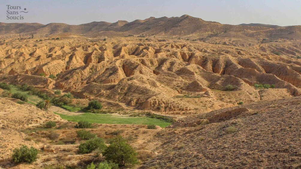 A rugged, eroded landscape with terraced hills and sparse vegetation. 1