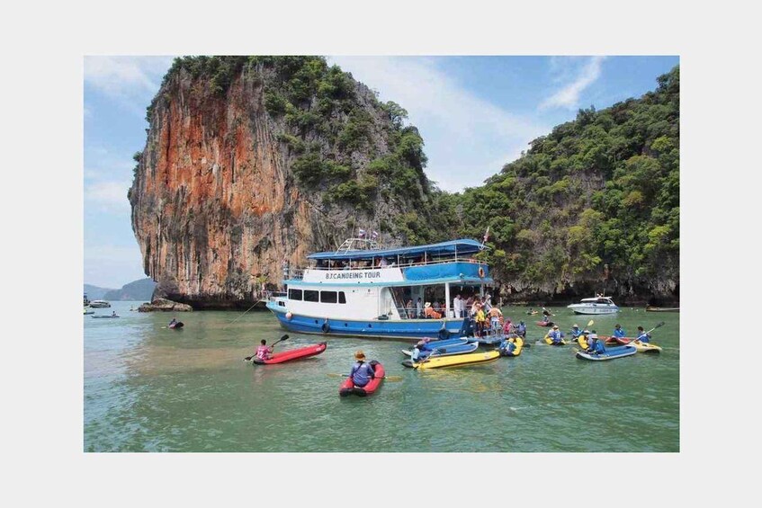 A boat tour with people kayaking in the water, surrounded by cliffs. 3
