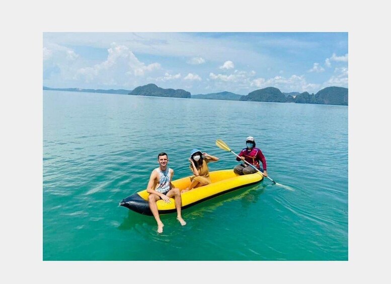 Three people on a yellow raft in calm turquoise water with distant mountains. 4