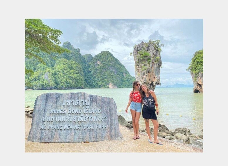A large rock with inscriptions, two people standing beside it, and a coastal landscape with cliffs and water. 5