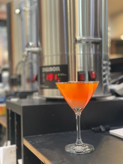 A martini glass with an orange drink on a bar counter. 3