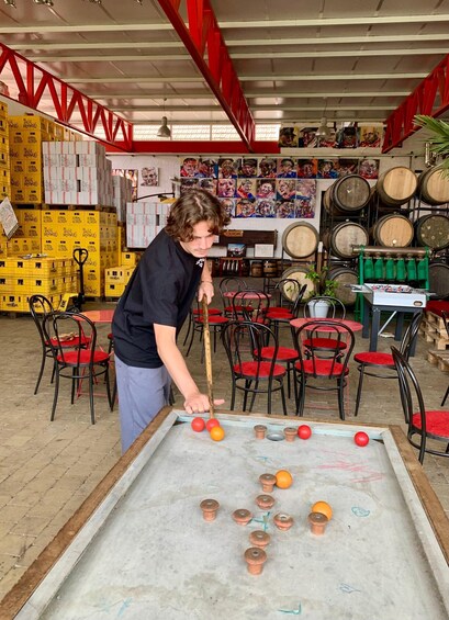 A person playing pool in a room with red chairs, wooden barrels, and various items on shelves. 2