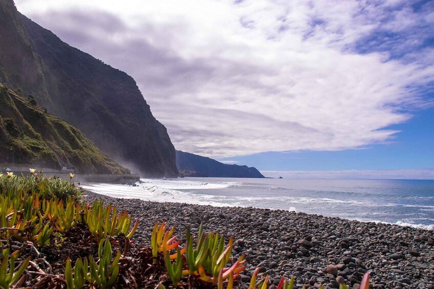 A coastal landscape with a rocky beach, ocean waves, and a mountain in the background. 3