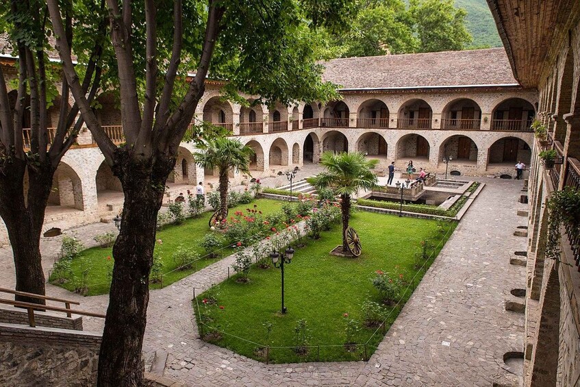 A courtyard with a central garden, surrounded by stone buildings with arched windows and balconies. 2