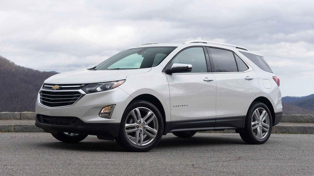 A white Chevrolet Equinox SUV parked on a road with a mountainous landscape in the background. 5