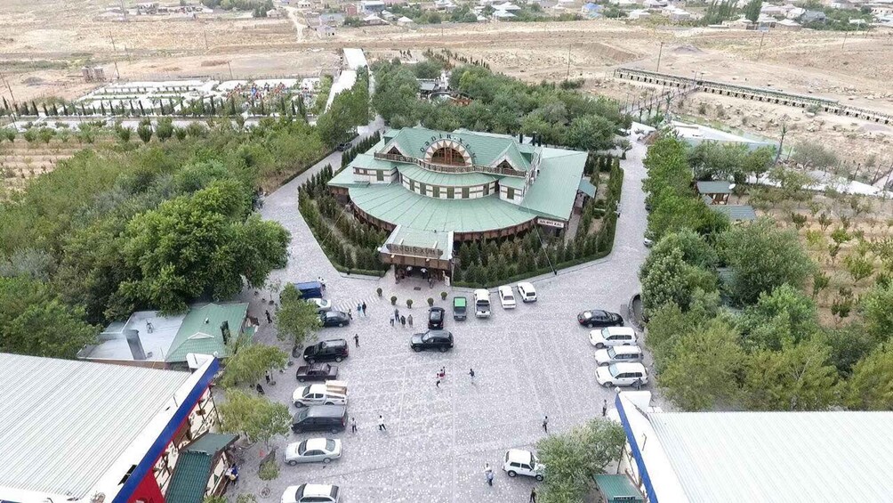A large, circular building with a green roof surrounded by a parking lot and trees. 4
