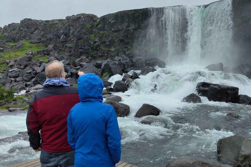 Two people standing on a wooden platform overlooking a waterfall. 5