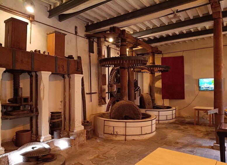 An old industrial building with large mechanical gears, wooden beams, and stone floors. 1