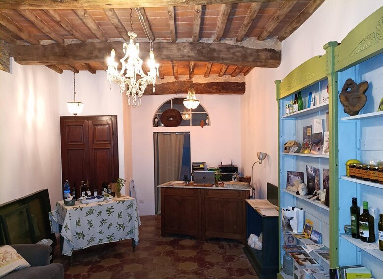 A rustic interior with wooden beams, a chandelier, a wooden door, a desk with a laptop, and a shelf with bottles. 3