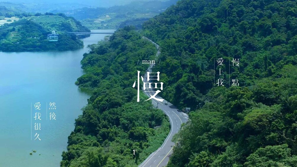 A winding road through a lush green landscape with a river on one side. 2