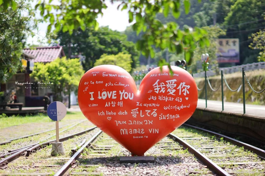Two heart-shaped signs with 'I LOVE YOU' written in multiple languages on a railway track. 1