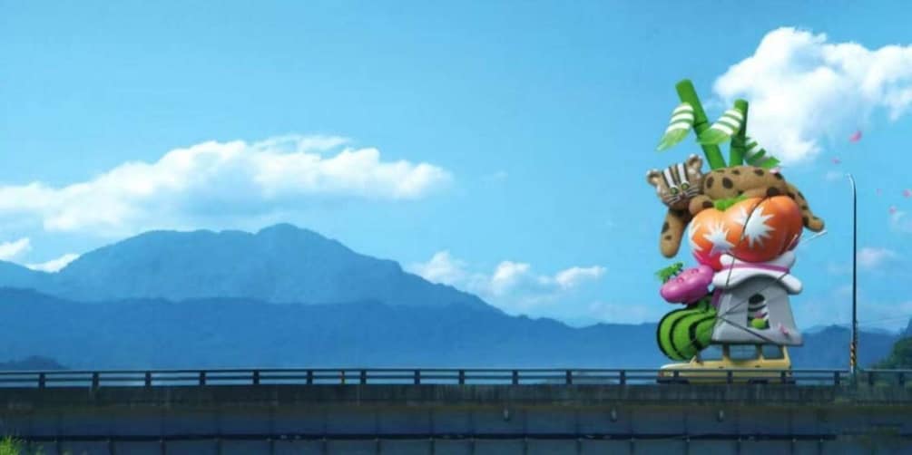 A colorful sculpture of a character with a large orange fruit on its back, set against a backdrop of mountains and a clear sky. 3