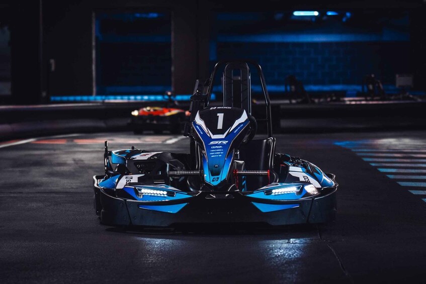 A go-kart in a dimly lit indoor setting with a blue and black color scheme. 1
