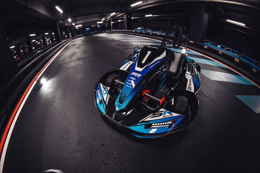 A go-kart on a track with a blue and black color scheme, surrounded by a curved track with blue and white markings. 2
