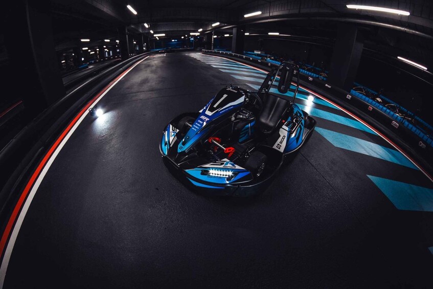 A go-kart on a track with blue and white stripes, a steering wheel, and a seat. 4