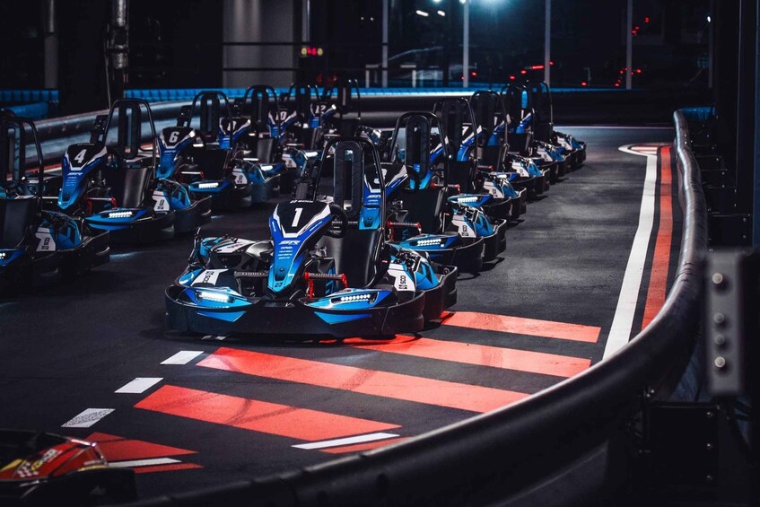 A racing track with multiple go-karts lined up at the starting line. 3