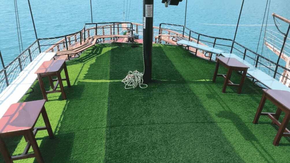 A deck with artificial grass, metal railings, and wooden tables and benches. 4