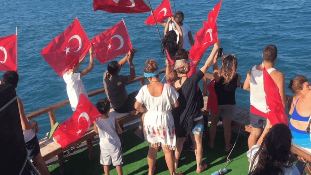 A group of people on a boat waving Turkish flags. 2