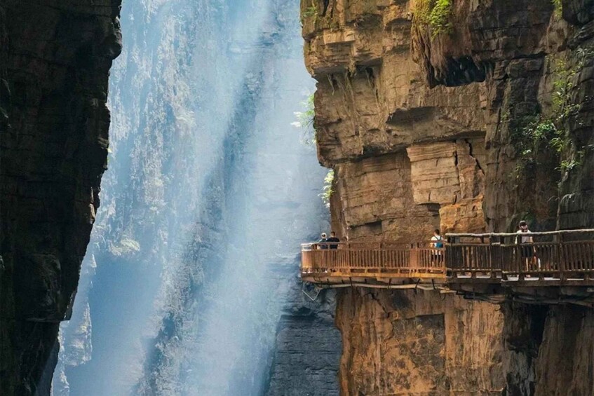 A wooden bridge over a canyon with people walking on it. 1