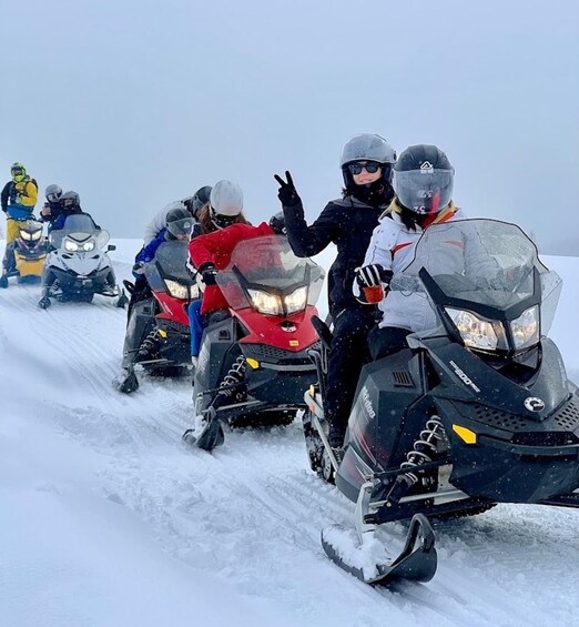A group of snowmobile riders on a snowy trail. 4