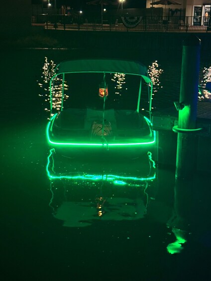 A car with green lights on the front, parked near a body of water at night. 1