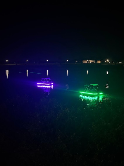 Two illuminated boats on a dark body of water with distant buildings. 5