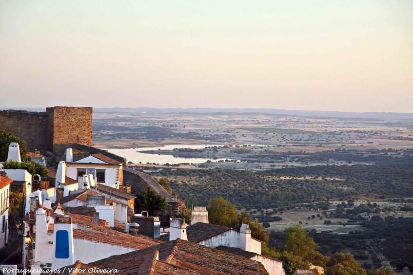A coastal town with white buildings and a large body of water in the distance. 5
