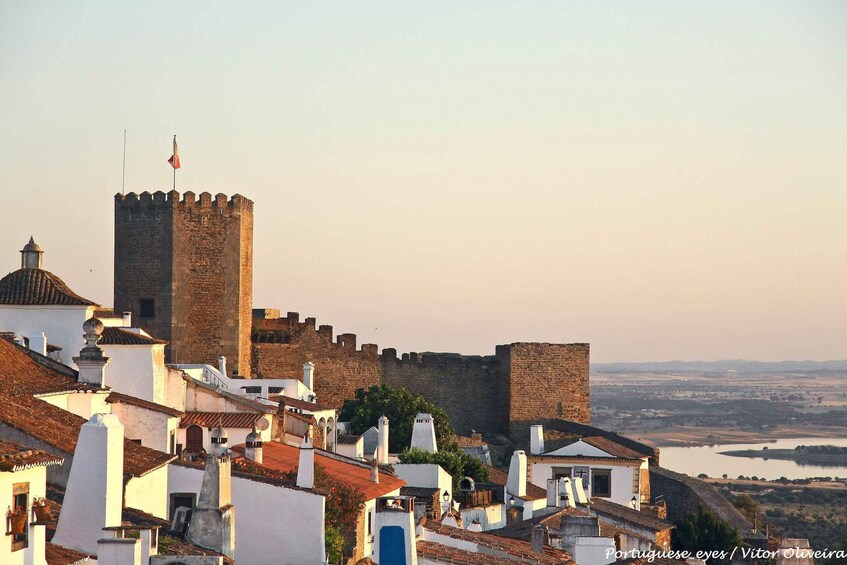 A historic castle with a flag, surrounded by traditional white buildings with red-tiled roofs. 4