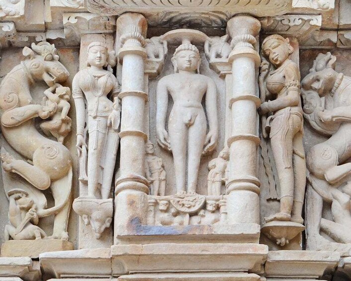 A detailed stone carving of a central figure flanked by animals and smaller figures, set within a temple or monument. 5