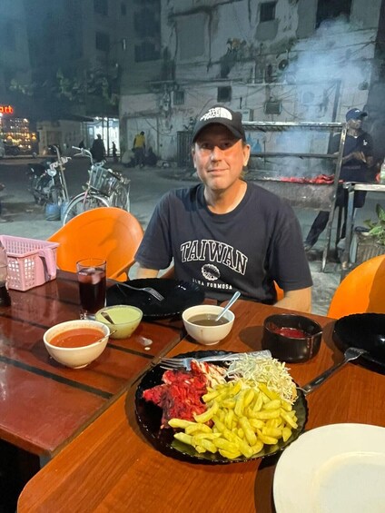 A person sitting at a table with a plate of food, bowls of soup, and a drink. 2