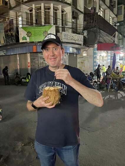 A person holding a coconut in an urban street scene at night. 3