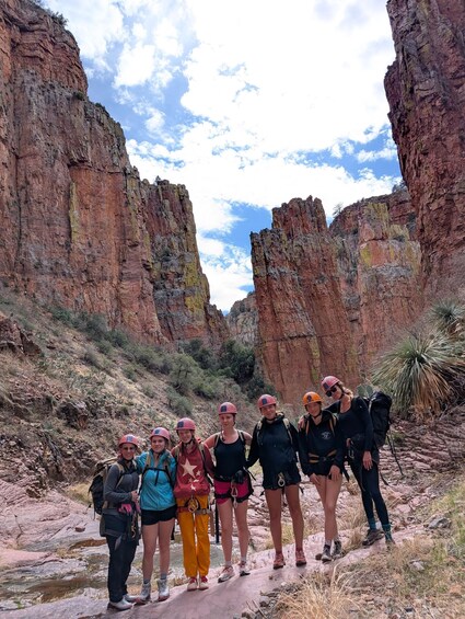 A group of people hiking in a canyon with red rock formations. 3