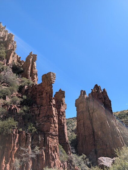 A rugged landscape with prominent red rock formations under a clear blue sky. 1