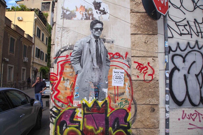 A street with graffiti, a man walking, and a car parked on the side. 2