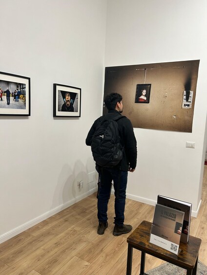 A person standing in an art gallery, looking at a large framed artwork on the wall. 5