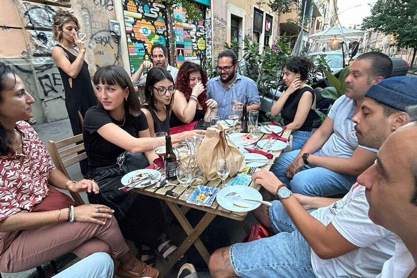 A group of people sitting around a table outdoors, engaged in conversation. 4