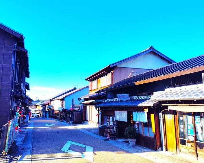 A narrow street lined with traditional buildings, some with signs and awnings, under a clear blue sky. 3