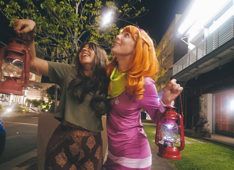 Two people holding lanterns, a building, and a tree. 5