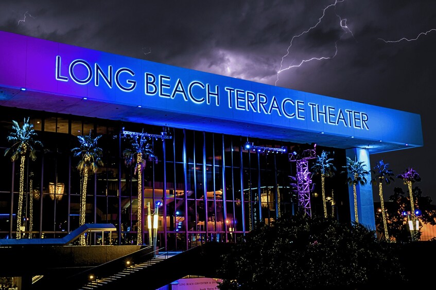 The exterior of the Long Beach Terrace Theater with illuminated signage and palm trees. 1