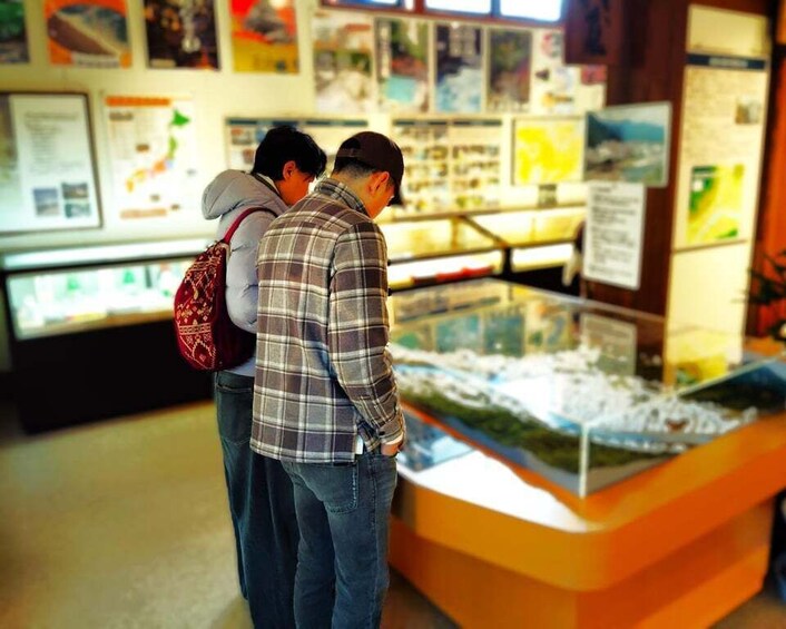 Two people examining an exhibit with informational posters in the background. 1