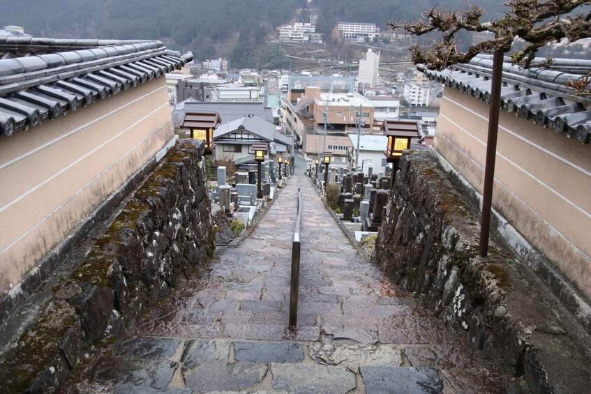 A traditional Japanese stone pathway leading to a temple with lanterns and a view of the city. 2