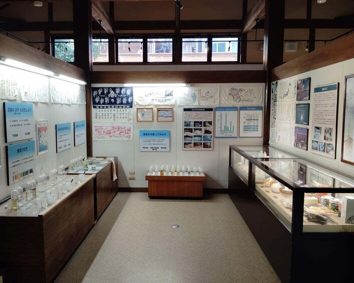 An indoor exhibition space with display cases, informational posters, and a central wooden table. 3