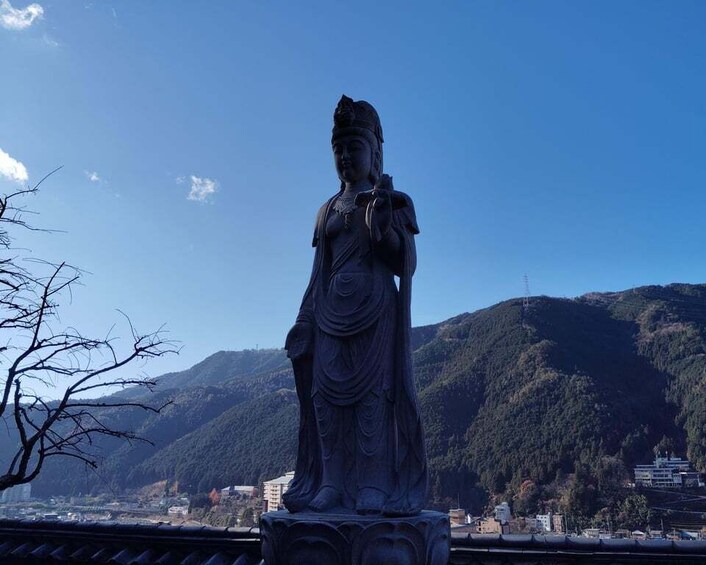 A statue of a figure in traditional attire, set against a backdrop of mountains and a clear sky. 4