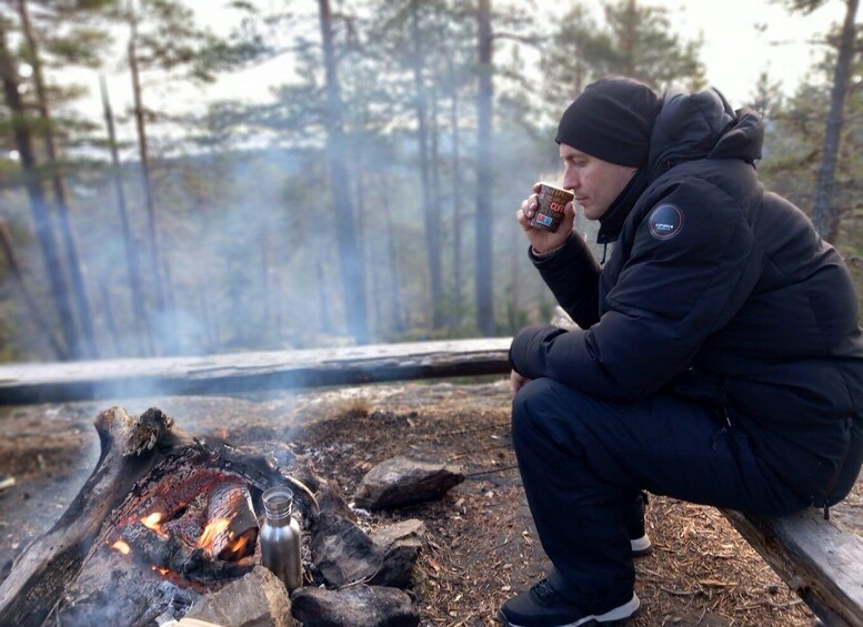 A person sitting by a campfire in a forest. 4