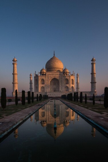 The Taj Mahal with its reflection in the water, four minarets, and a clear sky. 1