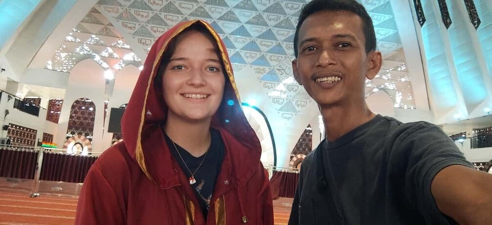 Two people taking a selfie inside a building with a high ceiling and patterned design. 5